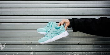 woman holding a pair of teal sneakers